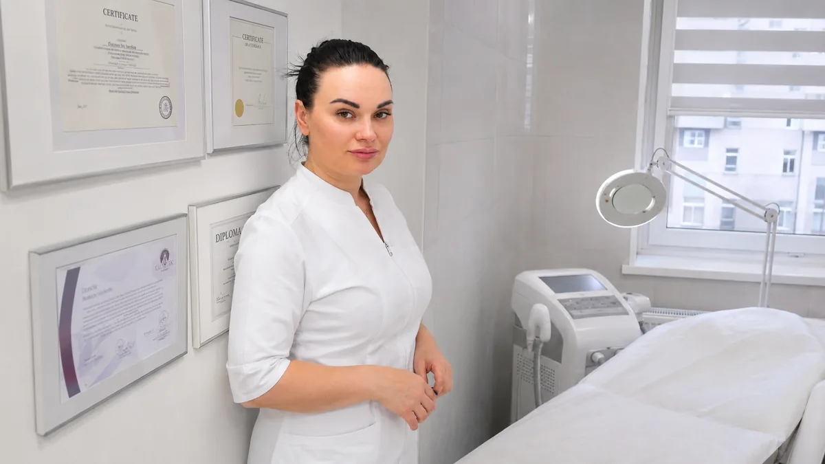 Врач-косметолог Шолоухова Т. у стены с сертификатами в кабинете